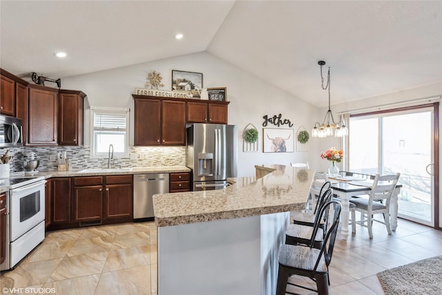 kitchen featuring pendant lighting, lofted ceiling, sink, a kitchen island, and stainless steel appliances