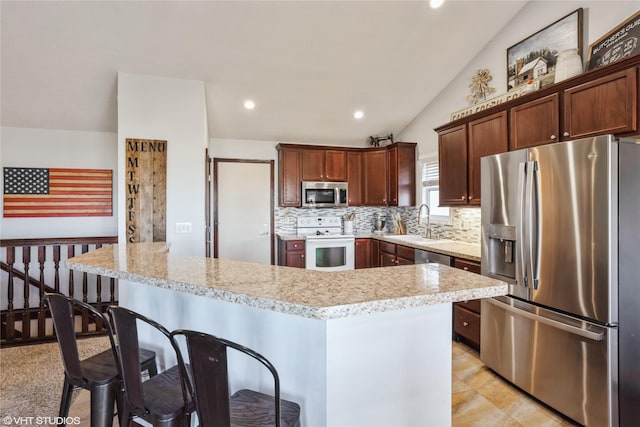 kitchen featuring a center island, sink, stainless steel appliances, lofted ceiling, and a breakfast bar