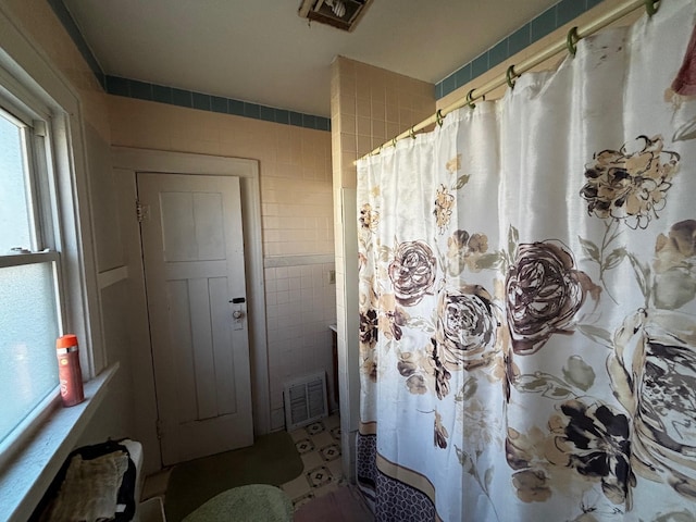 bathroom with curtained shower and tile walls