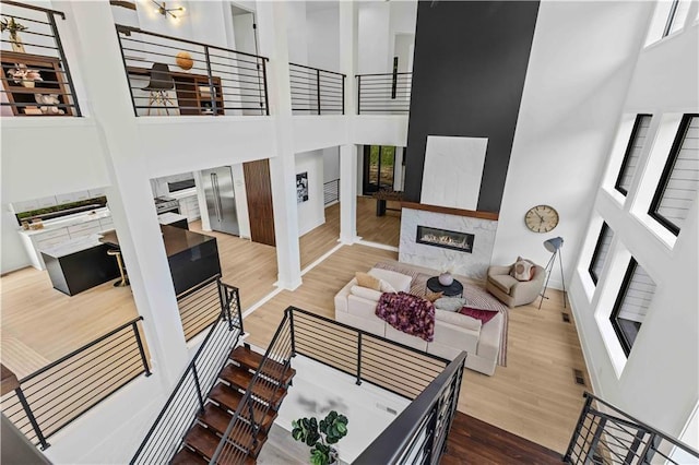 living room featuring a towering ceiling, hardwood / wood-style floors, and a fireplace