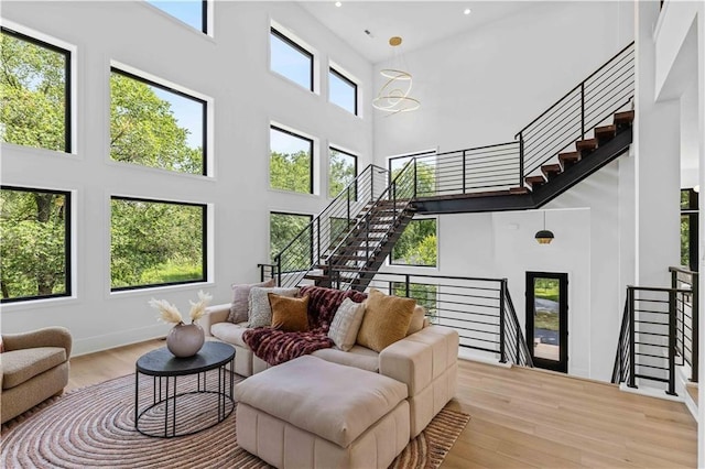 living room with a chandelier, light hardwood / wood-style floors, and a high ceiling