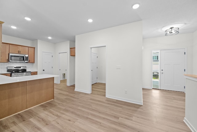 kitchen featuring light wood-type flooring, backsplash, and appliances with stainless steel finishes