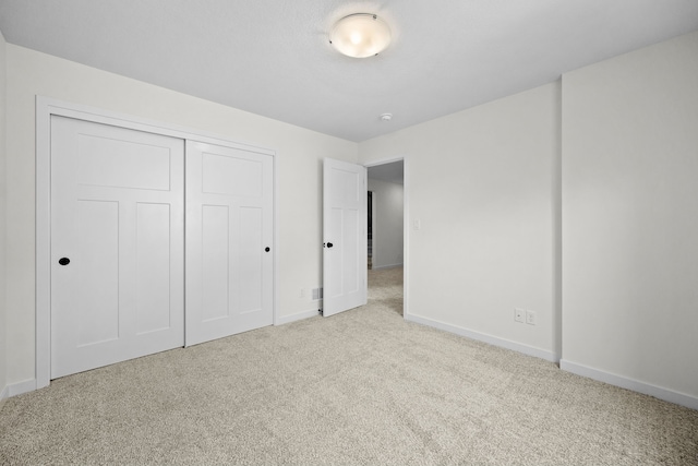 unfurnished bedroom with light carpet and a closet