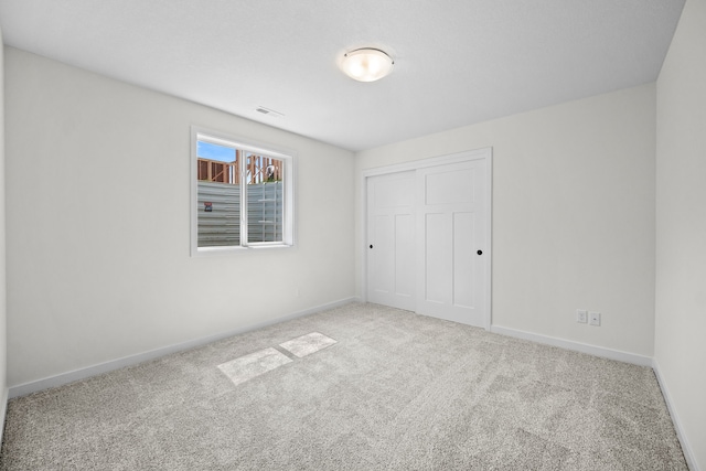 unfurnished bedroom with a closet and light colored carpet