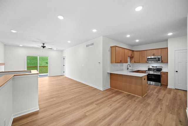 kitchen with ceiling fan, sink, stainless steel appliances, kitchen peninsula, and light wood-type flooring