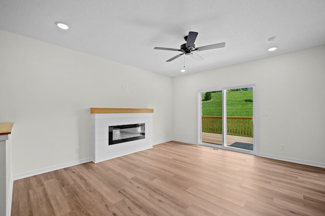 unfurnished living room featuring ceiling fan, light hardwood / wood-style floors, and a textured ceiling