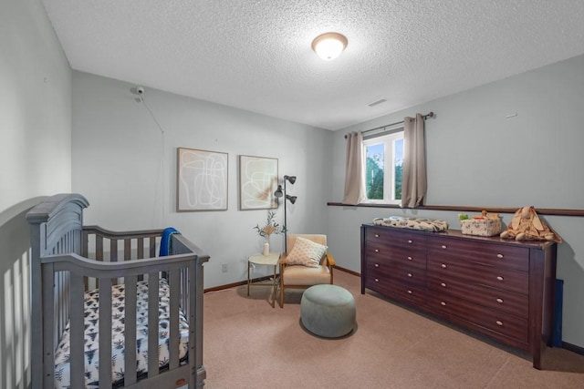 bedroom with light colored carpet, a crib, and a textured ceiling