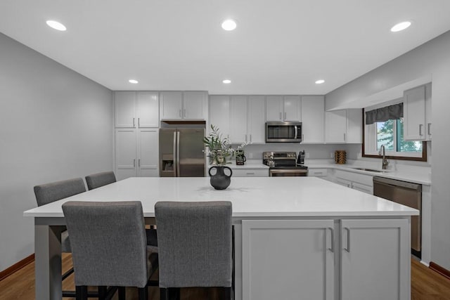 kitchen with a kitchen breakfast bar, a center island, sink, and appliances with stainless steel finishes