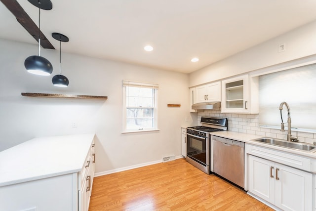 kitchen featuring white cabinets, pendant lighting, sink, and appliances with stainless steel finishes