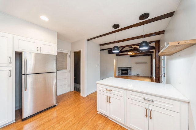 kitchen featuring pendant lighting, light hardwood / wood-style flooring, stainless steel fridge, beamed ceiling, and white cabinetry