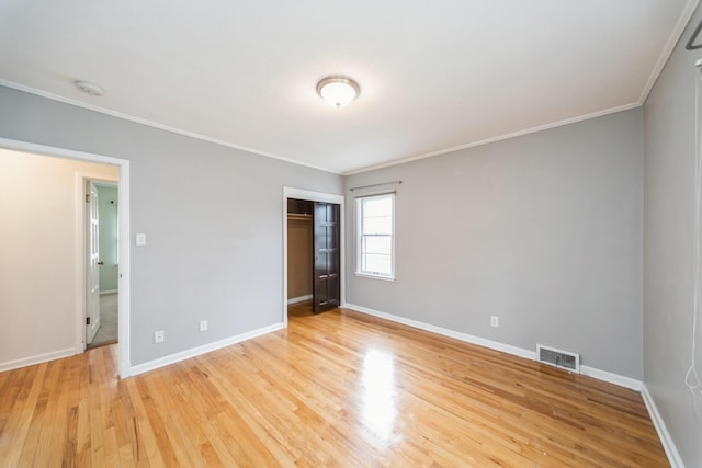 empty room with light wood-type flooring and crown molding