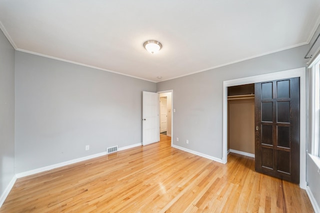 unfurnished bedroom featuring crown molding, a closet, and light wood-type flooring