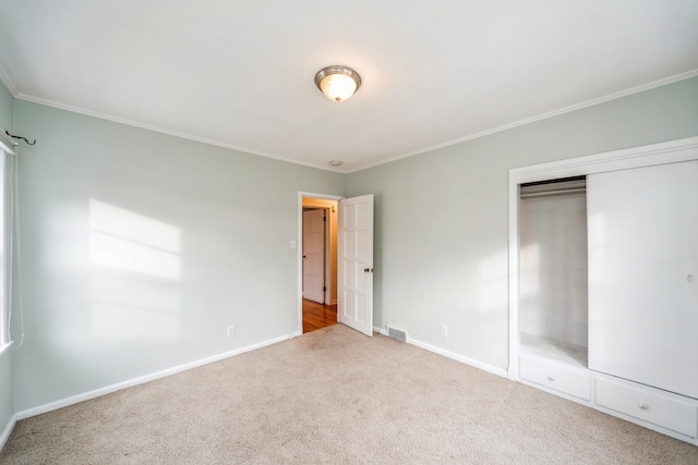 unfurnished bedroom featuring crown molding, a closet, and carpet