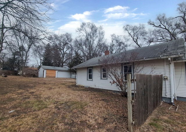 rear view of property featuring a garage and an outbuilding