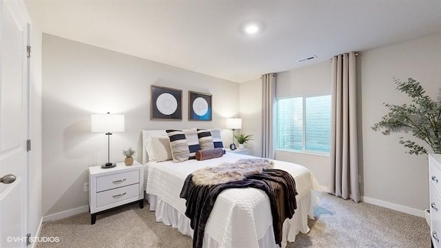 bedroom with baseboards, visible vents, and light colored carpet