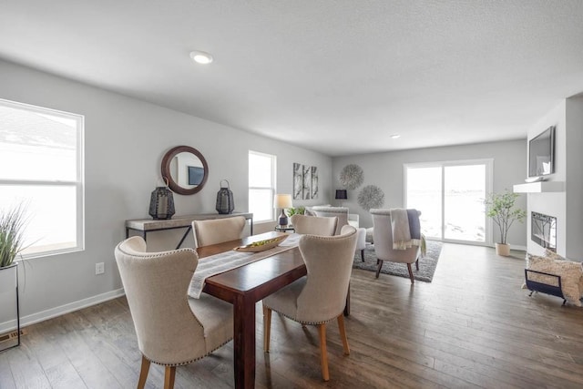 dining space with hardwood / wood-style floors, a fireplace, and a wealth of natural light