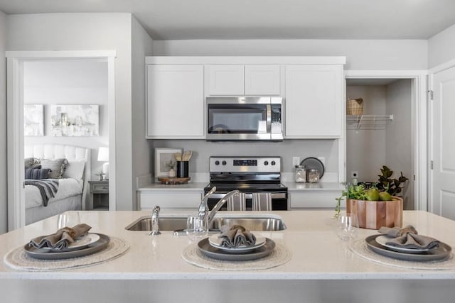 kitchen with appliances with stainless steel finishes, a sink, and white cabinetry