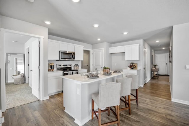 kitchen with appliances with stainless steel finishes, white cabinetry, a sink, and dark wood-type flooring