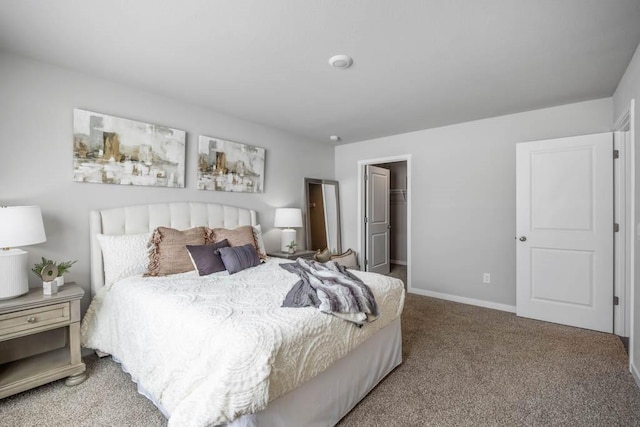 carpeted bedroom featuring a walk in closet, a closet, and baseboards