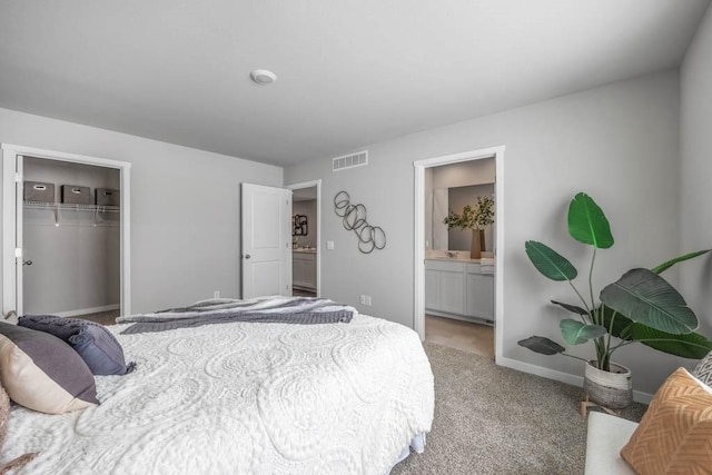 bedroom featuring a closet, light colored carpet, visible vents, connected bathroom, and baseboards