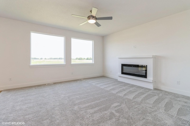 6802 SE 7th Ave, Pleasant Hill, IA 50327 - unfurnished living room featuring a glass covered fireplace, ceiling fan, and light colored carpet