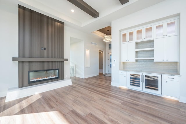 bar with tasteful backsplash, a large fireplace, white cabinets, and hanging light fixtures