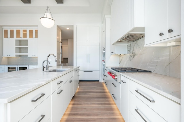 kitchen with pendant lighting, white cabinets, sink, paneled refrigerator, and stainless steel gas cooktop