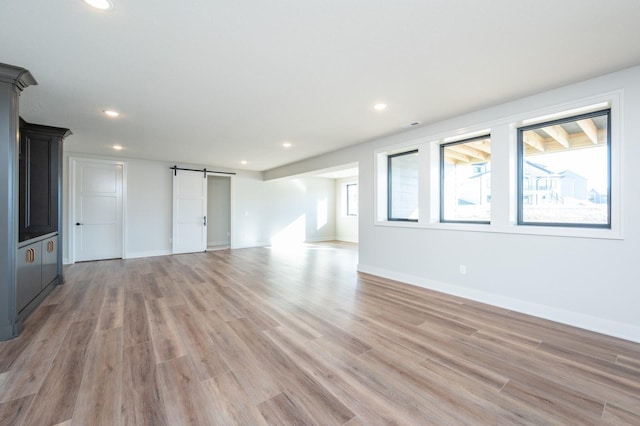 unfurnished living room featuring a barn door and light wood-type flooring