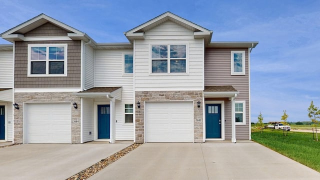 view of property with stone siding, an attached garage, and concrete driveway