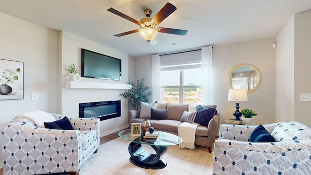 living room with a ceiling fan, a glass covered fireplace, and baseboards