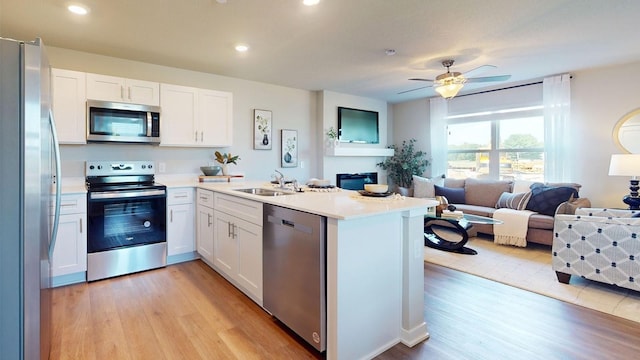 kitchen featuring a peninsula, appliances with stainless steel finishes, open floor plan, and a sink