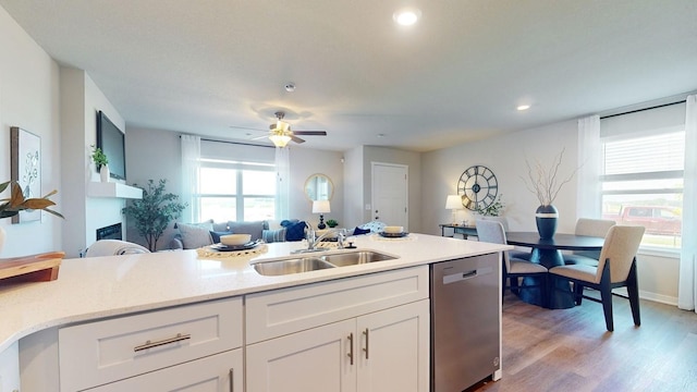 kitchen with open floor plan, white cabinetry, a sink, light wood-type flooring, and dishwasher