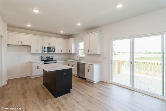 6918 SE 7th Ave, Pleasant Hill, IA 50327 - kitchen with appliances with stainless steel finishes, a kitchen island, light wood-type flooring, light countertops, and white cabinets