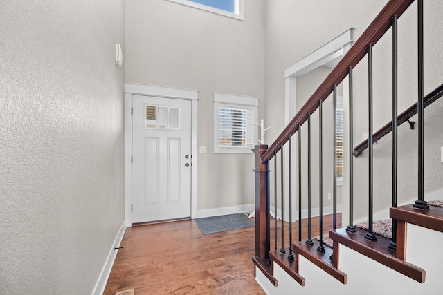 entryway with a towering ceiling and wood-type flooring