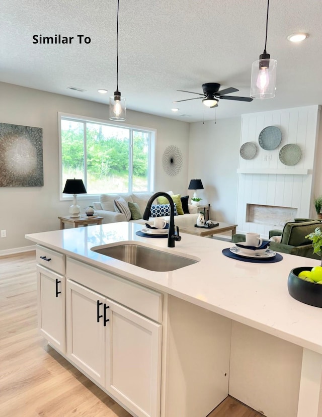 625 W Wright Rd, Norwalk, IA 50211 - kitchen featuring a sink, open floor plan, a textured ceiling, pendant lighting, and light countertops