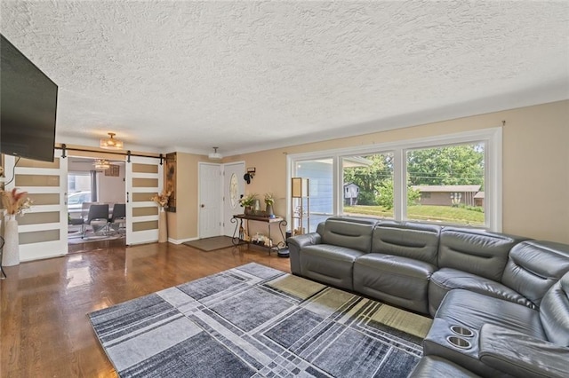 living room with dark hardwood / wood-style flooring, a textured ceiling, a barn door, and a healthy amount of sunlight