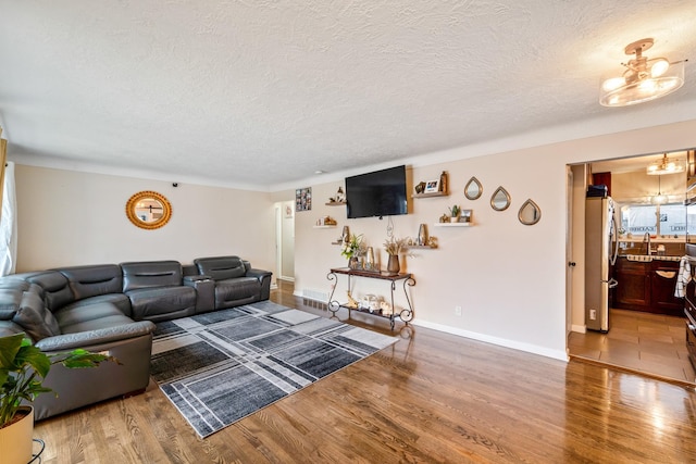 living room with sink, wood-type flooring, and a textured ceiling