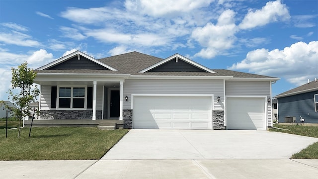 view of front facade featuring a porch, concrete driveway, an attached garage, stone siding, and a front lawn