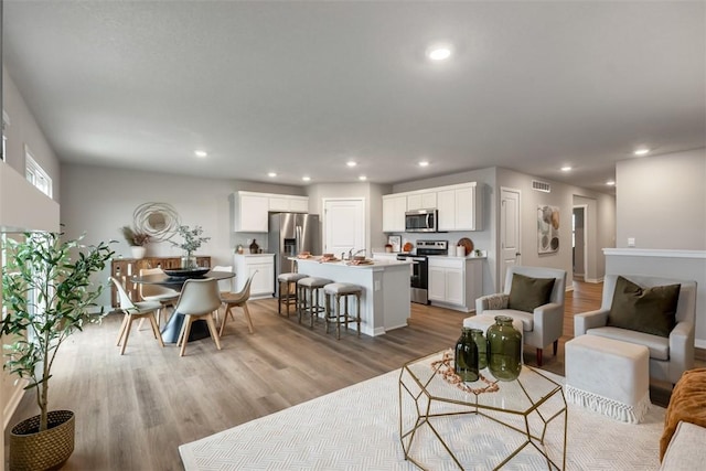living area featuring recessed lighting, visible vents, and light wood-style floors