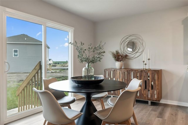 dining space with light wood-type flooring and baseboards