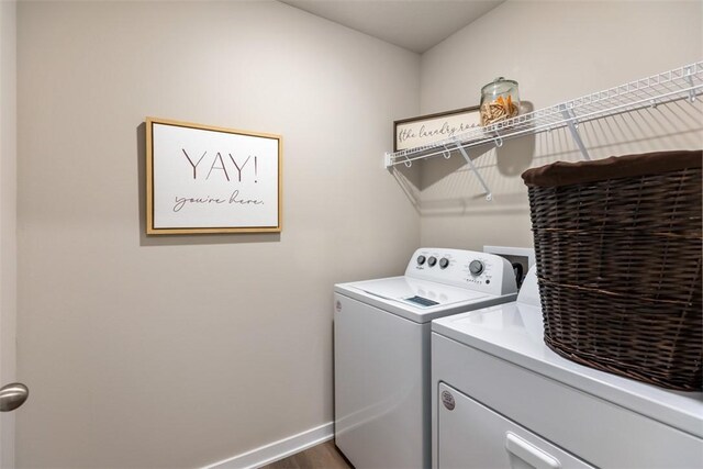 clothes washing area with laundry area, washing machine and dryer, and baseboards