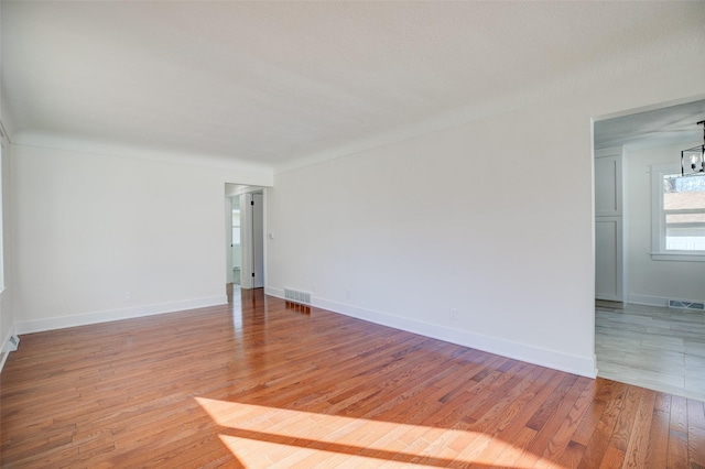 spare room with light hardwood / wood-style flooring and a notable chandelier