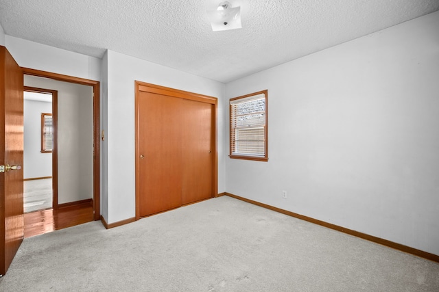 unfurnished bedroom with carpet flooring, a closet, and a textured ceiling