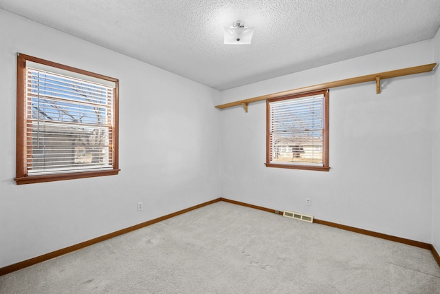 carpeted spare room with a textured ceiling