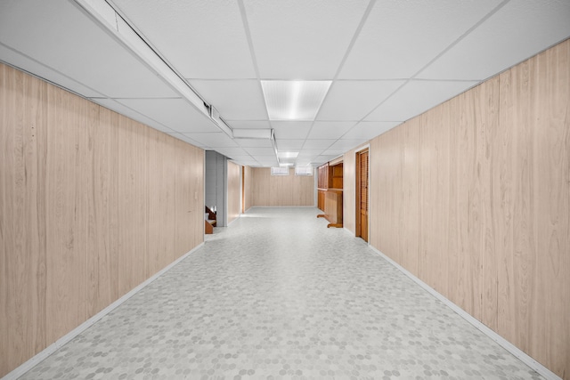 hallway featuring a drop ceiling and wooden walls