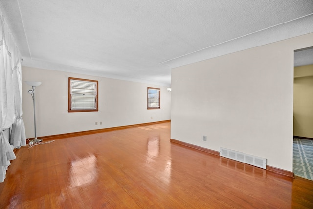 empty room featuring a textured ceiling and light hardwood / wood-style floors