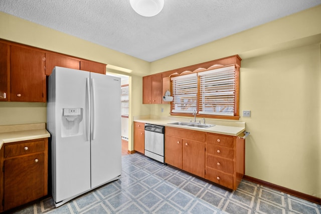 kitchen with stainless steel dishwasher, white fridge with ice dispenser, sink, and a textured ceiling