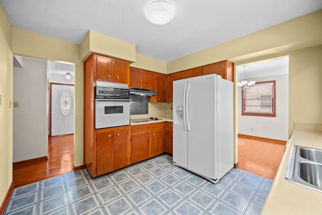 kitchen with sink, light hardwood / wood-style floors, white appliances, and a notable chandelier