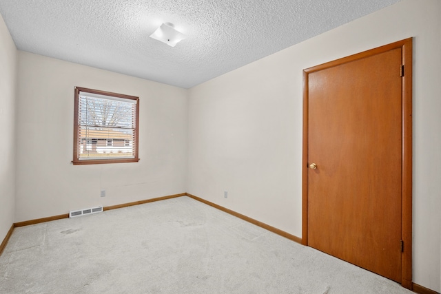 unfurnished room featuring light carpet and a textured ceiling