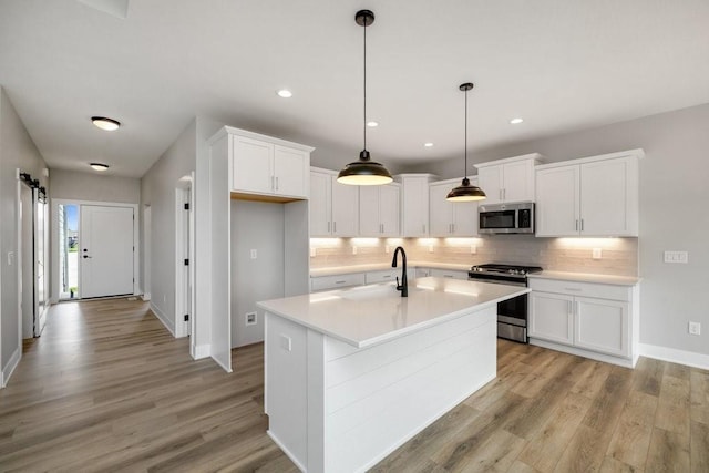 kitchen featuring decorative backsplash, white cabinetry, stainless steel appliances, and hanging light fixtures